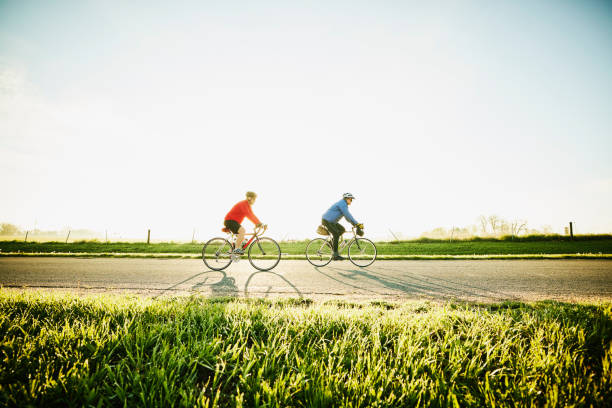 Two friends cycling on a country road at sunrise